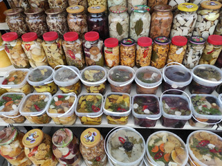 large selection of wild mushrooms. homemade delicious marinated mushrooms in glass jars. glass jars with wild mushrooms. assortment of mushrooms on shelves.