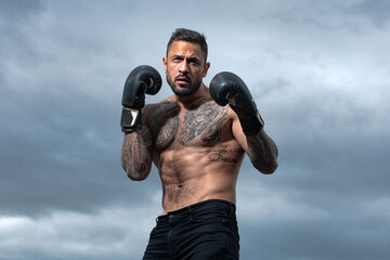 Sport boxing. Sportsman boxer fighting on sky background. Strong athletic man with boxing gloves...