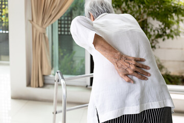 Hand of asian old elderly touch lower back muscles,senior patient with walker stick,suffering from...