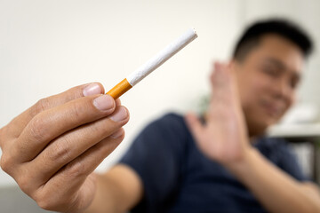 Hand of male smoker holding a cigarette,raising hand to refuse smoking,practice of restraining oneself from drug addiction,asian man rejecting cigarette,Say No,Stop,quit smoking,health care concept