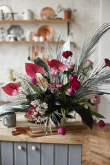 Exotic flowers composition on the wooden table of the cozy kitchen