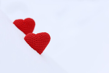 Love hearts, Valentine's card, two red knitted symbols of passion in the snow. Background for romantic event, celebration or winter weather