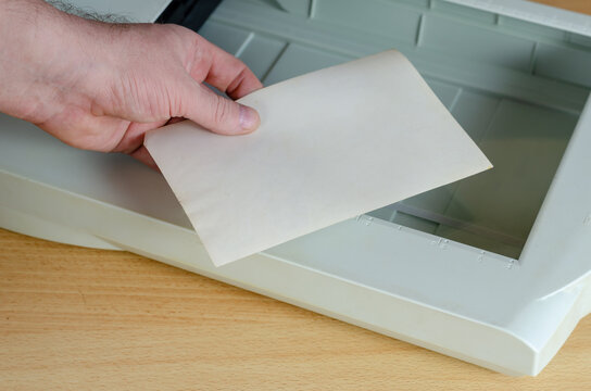 Digitization of a family photo album. A hand places a paper phot