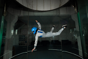 A young woman in overalls and a protective helmet enjoys flying in a wind tunnel. Free fall...