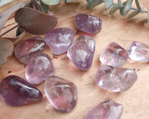 amethyst purple crystal tumbled semi precious stone, senitransparent rock, on raw natural wood with...