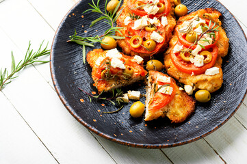 Meat schnitzel with cheese, olives and tomato