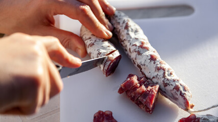 Men's hands cut french cured sausage with white mold