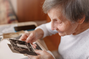 Mature woman watching black and white old photo album at home. Grandmother is looking at her own...