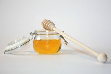 A jar of honey with a wooden spoon.