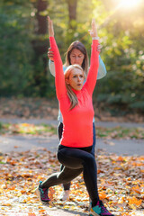 Women Stretching with Personal Fitness Trainer After Training in The Park.