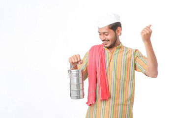 Young indian common man in traditional wear holding tiffin box in hand on white background.