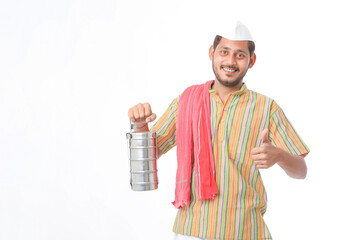 Young indian common man in traditional wear holding tiffin box in hand on white background.