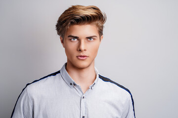 portrait of handsome young man wearing shirt while looking at camera. Stylish hairstyle. 