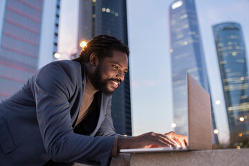 handsome afro american businessman using computer at night in city buildings