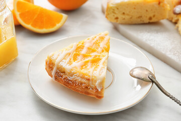 Plate with slice of tasty citrus cake with oranges on table