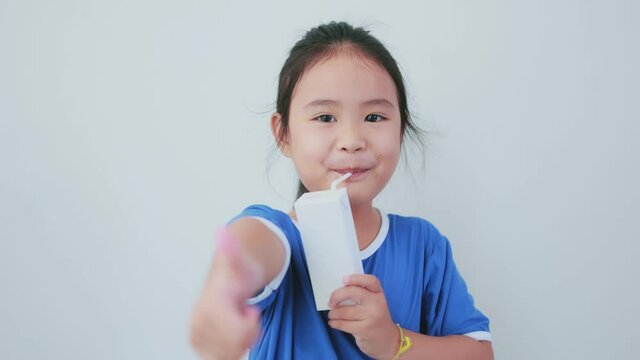 Asian girl drinking white milk carton with thumbs up showing deliciousness. Half body on white background.