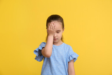 Portrait of tired little girl on yellow background