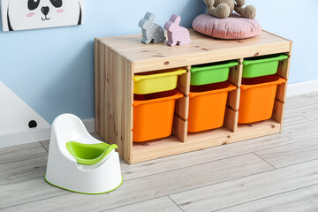 White potty and drawers on grey wooden floor near color wall