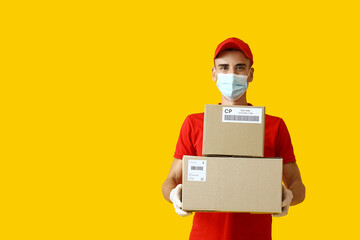 Fototapeta na wymiar Male courier in medical mask and with parcels on color background