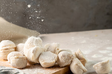 Flour is sprinkled on raw homemade dumplings. Traditional Russian dumplings.