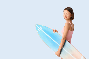 Beautiful young woman with surfboard on light background