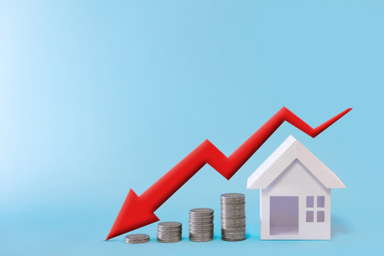 Stack Of Coins Arranged In Ascending Order With House Model And Green Arrow Graph Reduced Value In Blue Background For Business Investment Real Estate Concept.