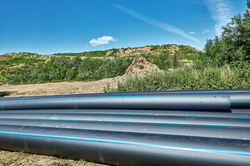 Polyethylene pipes are laid pipes lying against the background of a roadside yard with a copying platform.