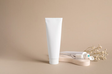Composition with toothpaste tubes, toothbrush and flowers on beige background