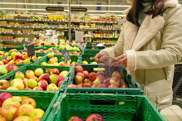 woman choosing apples put in bag groceries store
