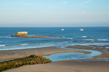 Fototapeta na wymiar Deux chalutiers doublent le Fort de l'Heurt au large de la plage de Le Portel