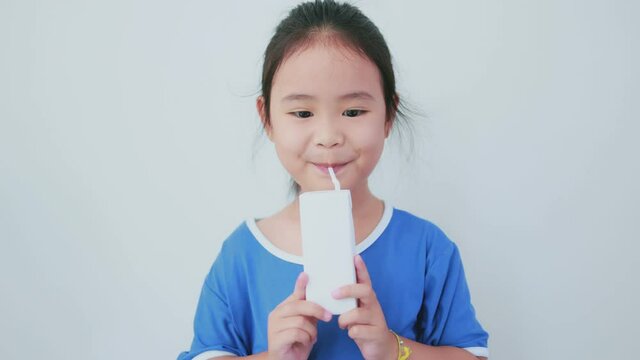 Asian girl holding a white milk carton and drinking deliciously while smiling happily.Half camera angle on white background.