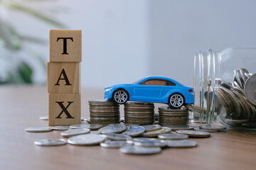 Car tax concept.close up stack of coins and tax wooden text with toy car.saving money for...