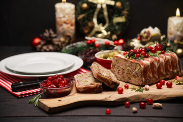 Traditional French terrine covered with bacon on dark wooden background with Christmas decorations