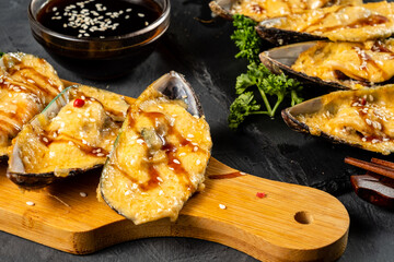 Mussel snack. Baked mussels with cheese on a wooden board. Close-up. Selective focus.