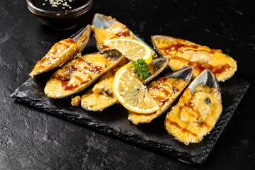 Mussels baked with cheese served on a dark stone for serving. Dark table. Mussel snack.