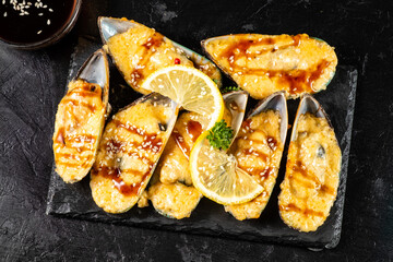 Mussels baked with cheese and teriyaki sauce. View from above. Dark table. close-up