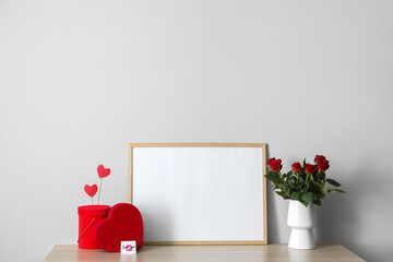 Gifts for Valentine's Day and flowers with empty photo frame on table in room