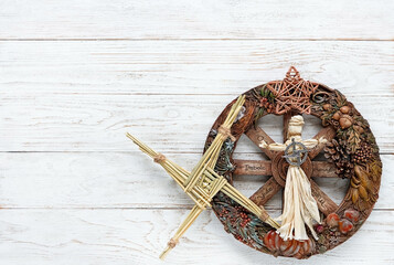 Wiccan altar for Imbolc sabbat. pagan festive ritual. wheel of the year, Brigid's cross from straw, amulet, witchcraft doll on white wooden table. Imbolc holiday, spring equinox. flat lay. copy space - obrazy, fototapety, plakaty
