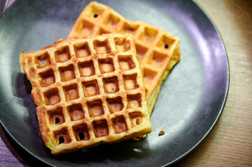 Zwei belgische Waffeln frisch auf dem Waffeleisen liegen auf einem fettigen und benutzten Teller