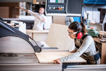 male and female carpenter at work, man and woman are crafting with wood in a workshop