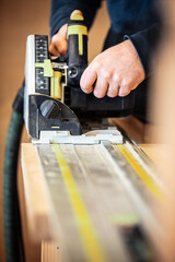 carpenter or craftsman cuts wood with an electric circular saw