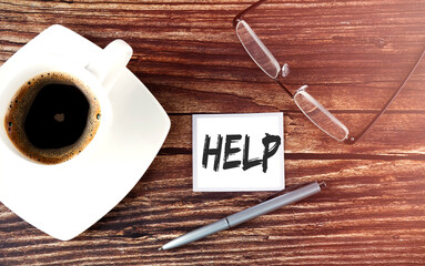 HELP text on sticky with coffee,pen and glasses on the wooden background