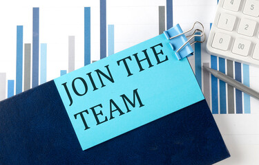 JOIN THE TEAM on sticky note on the notebook on the chart background