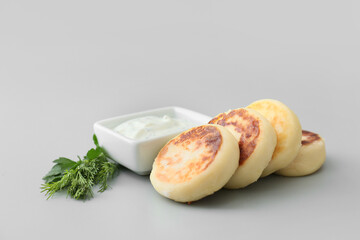 Tasty cottage cheese pancakes and sauce on grey background