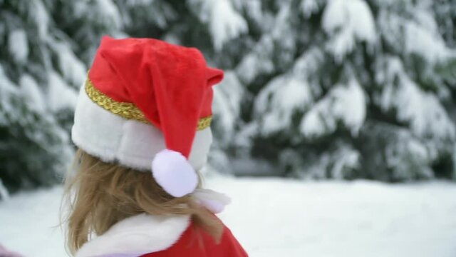 Portrait Happy christmas girl run away in santa costume in snow. Winter forest with snowdrifts and snacks. child laughs at new year and walks back outside. red suit hat. Dance have fun. childhood.