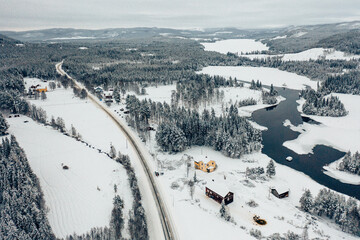Winterlandschaft mit der Drohne in Schweden mit Seen, Bergen, Wald und einem gelben, einsamen Haus 