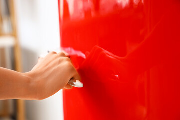 Woman opening red fridge in kitchen, closeup