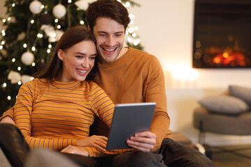 Smiling young couple using digital tablet at home