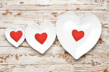 Beautiful heart shaped plates on white wooden background