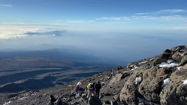 Amazing panorama from Mount Kilimanjaro. Climbing Kilimanjaro in December Several tourists climb up the mountain. View of Mount Mawenzi in the clouds.